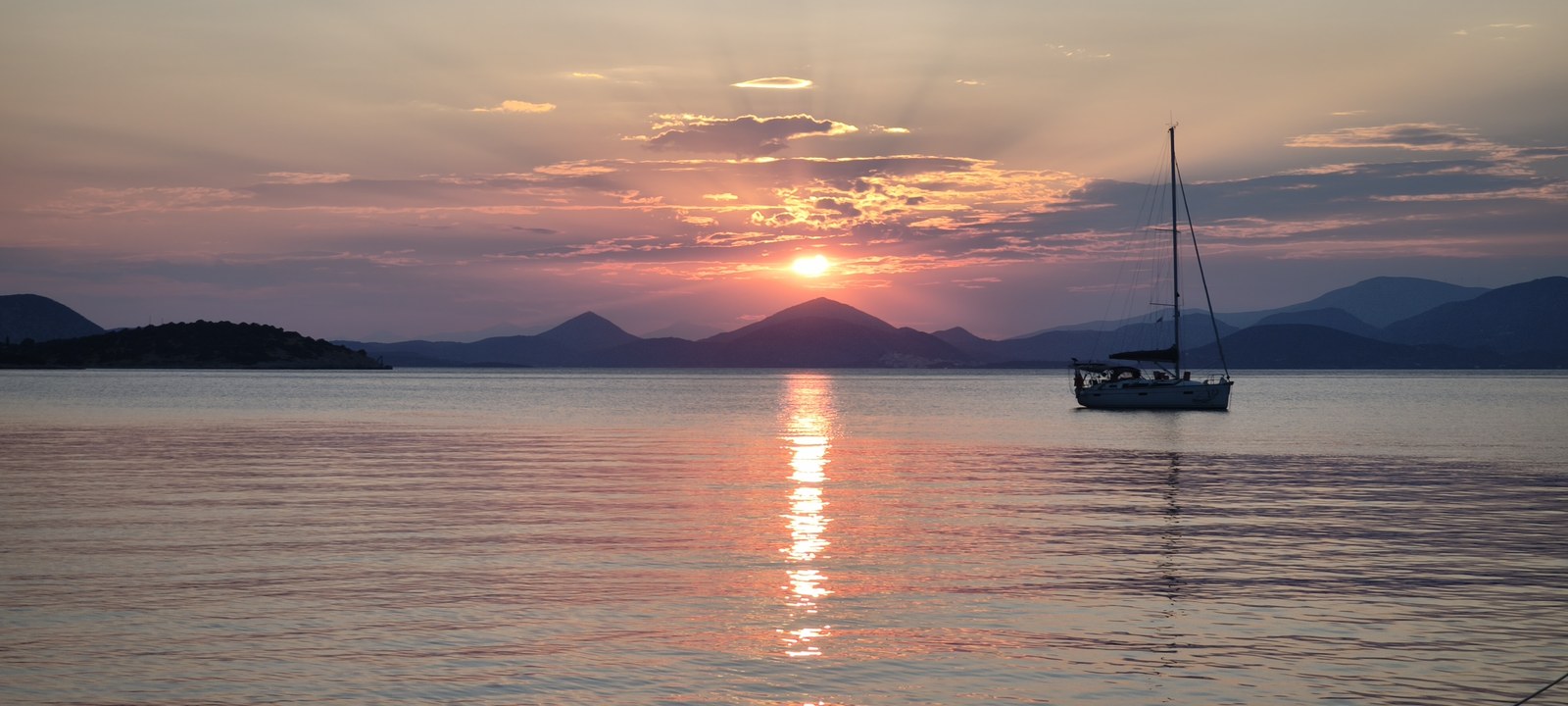 Velero fondeado al atardecer, bahía desierta