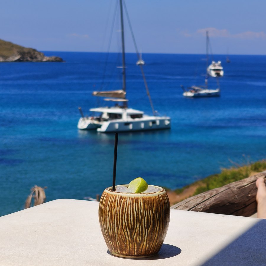 A drink on a white wall, catamaran at anchor