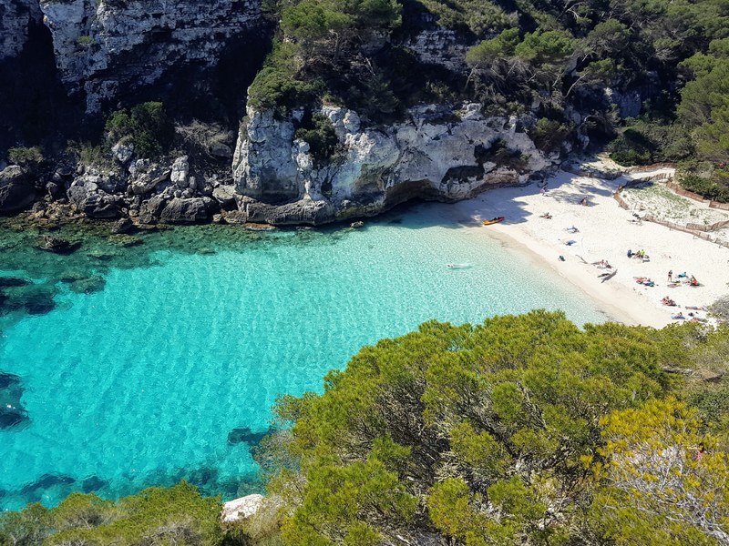 The turquoise cove of Cala Macarelleta in April, seen from the cliff