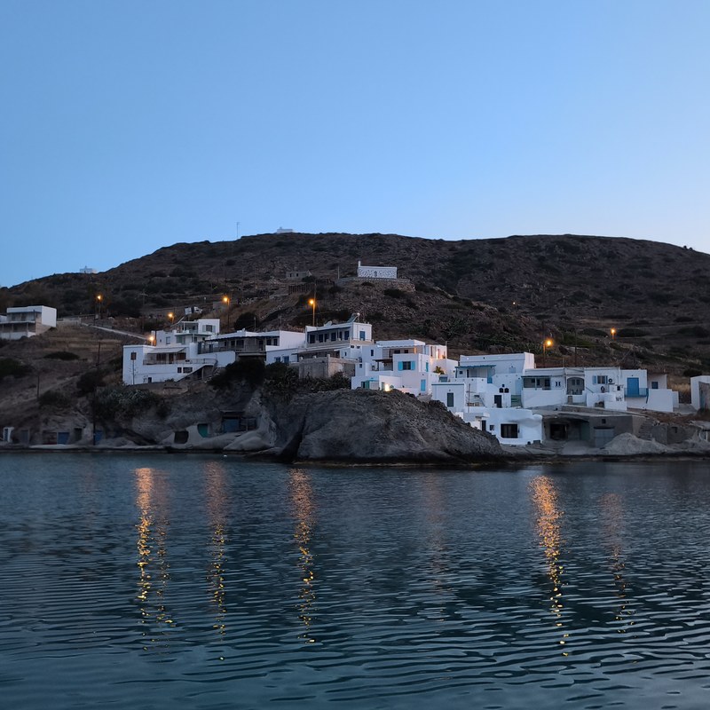 A Kimolos bay at dusk, white village above the water, Cyclades, Greece